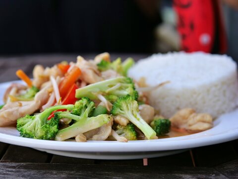  An eye-level, selective 
focus close-up shot of a plate of Asian 
chicken stir-fry. The dish features 
vibrant green broccoli florets, sliced red 
bell peppers, carrots, and bean sprouts 
in a savory