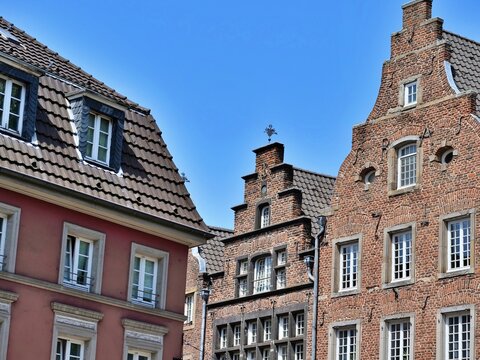 A scenic architectural 
photograph showcasing a row of historic 
buildings in a German old town. The 
composition features a red plastered 
building with a dormer window