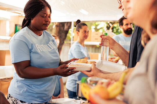Multiethnic team in a community center provides food and support to the less fortunate including poor and homeless people, voluntary individual offering a meal to a needy hungry person.