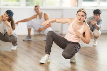 Fototapeta premium Group of young friends learn group dances - hip-hop and breakdance in a dance studio