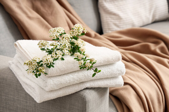 Fresh white towels stacked with delicate spirea flowers for spa, relaxation, and home comfort