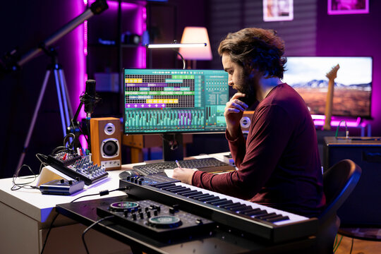Young producer writing rhymes and words to create new music in home studio, thinking about harmonic notes and elements to compose a beautiful song, with audio engineer produces tunes.