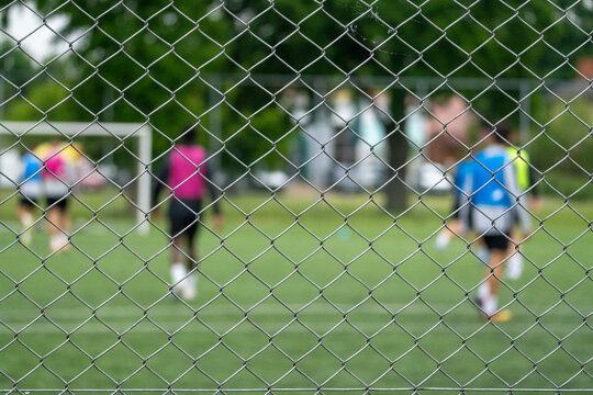 Amateur Soccer Players Behind Chain Link Fence on Outdoor Football Field
