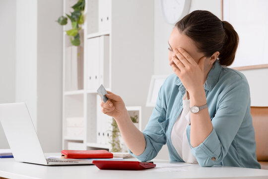 Stressed woman holding credit card at desk, financial debt and budgeting problems, online shopping and payment issues