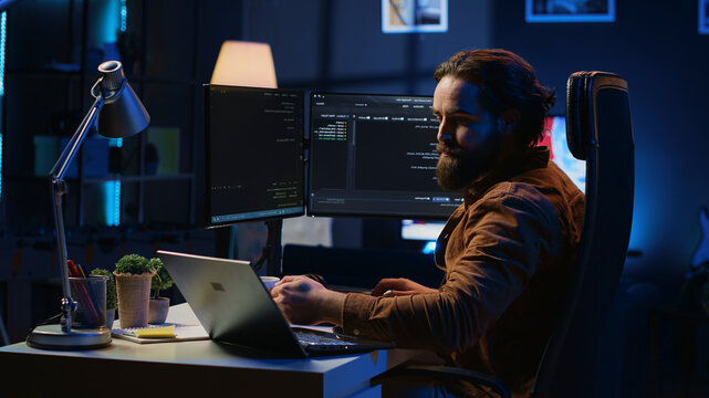 Software programmer putting headphones on while developing code, making time pass faster during remote job shift.