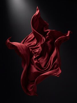 Abstract flowing red silk fabric floating in the air against a dark background with dramatic studio lighting