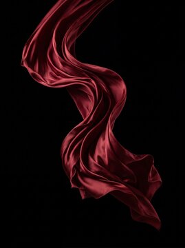 Elegant red silk fabric flowing gracefully against a solid black background