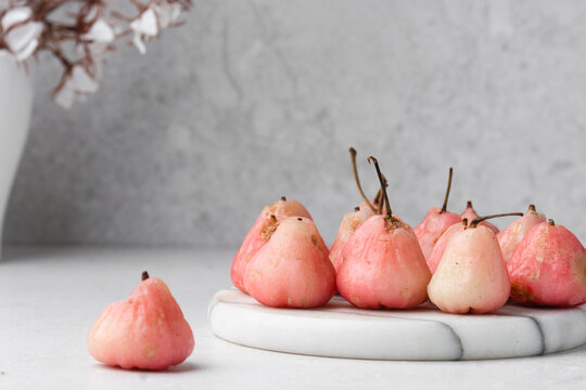 Light pink rose apples on a white marble tray, closeup view of rose wax apples on textured white background