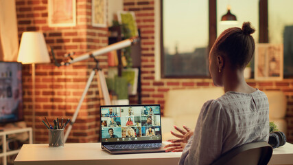 Fototapeta premium African American girl on videocall doing briefing meeting for new research plan to solve online tasks.