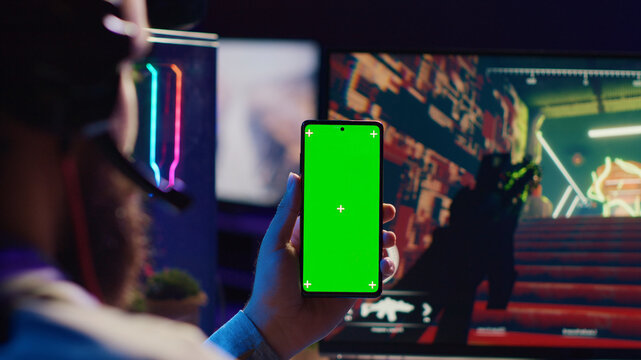 Man watching favorite content creator on green screen smartphone showing tips for game he is currently playing, close up.