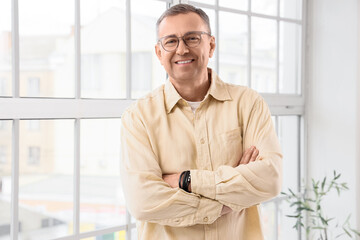Fototapeta premium Confident mature man in glasses with arms crossed professional business portrait positive expression modern office setting