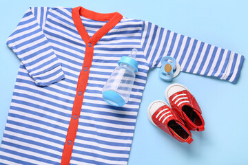 Obraz premium Baby shower gift set with striped bodysuit, red shoes, pacifier, and bottle on blue background