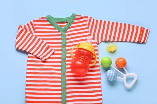Baby shower gift set with striped bodysuit, sippy cup, pacifier, and rattle on blue background