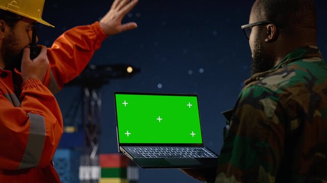Green screen laptop, talking into handheld radio and soldier on drilling rig during oil crisis while speaking into walkie talkie, mockup notebook and armed guard on offshore platform.