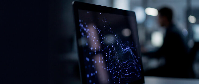Digital data visualization on screen with blurred businessman in dark office