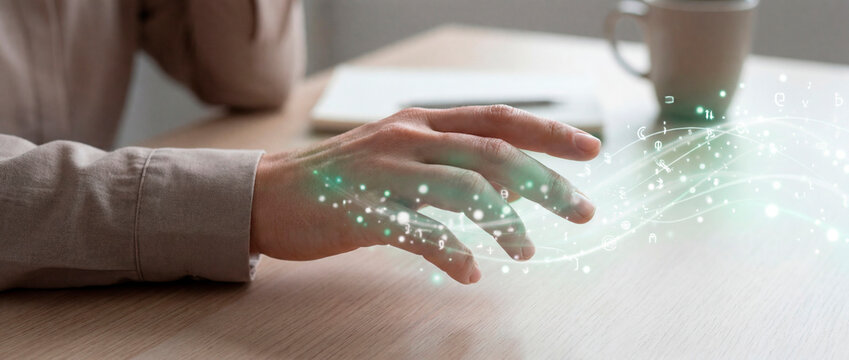 Adult hand interacting with floating digital characters above wooden office desk