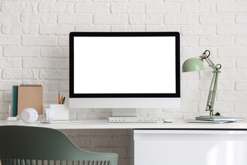 Fototapeta premium Modern home office workspace with blank computer screen, white brick wall background, and minimalist desk setup