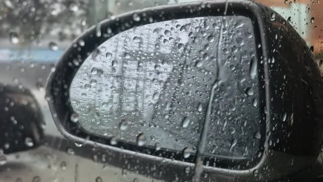 Close-up of raindrops on a car's side mirror during a downpour
