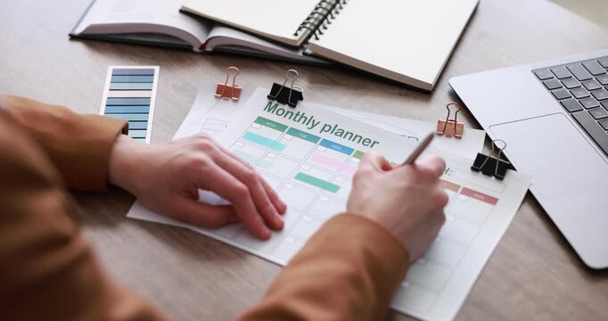 Woman with monthly planner at wooden desk, closeup