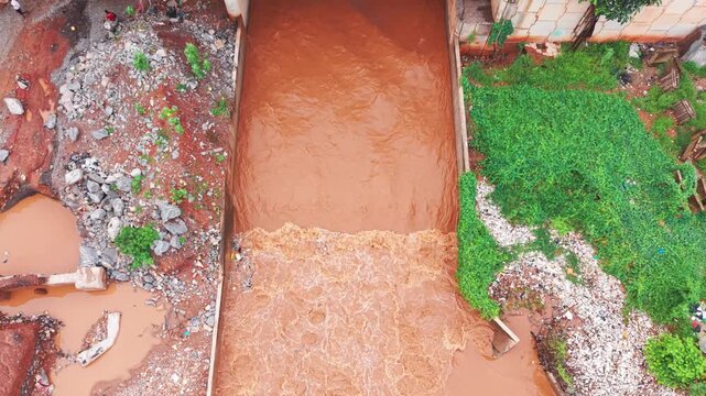 Aerial view, Muddy floodwaters rushing through an overflowing storm drain in accra, ghana