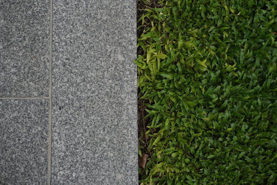 Juxtaposition of rough granite tiles and lush green grass in a garden setting
