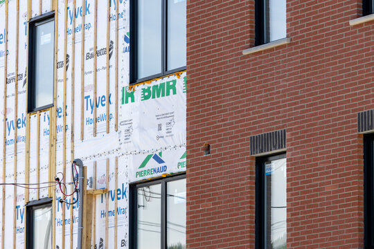 La Tuque, Quebec, 23 May 2026 : A building under construction features Tyvek HomeWrap insulation and wooden battens next to a finished brick facade.