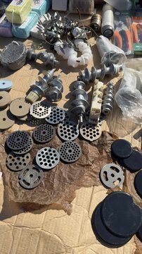 Assorted metal and plastic grinder nozzles laid out on wooden workbench with milling cutter bits round perforated plates dies