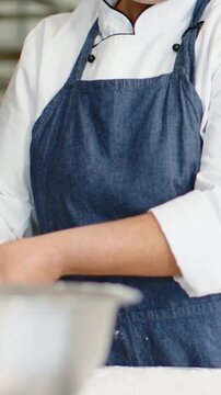 Vertical video: Kneading chef in apron with hands in bowl at counter making dough holding cloth