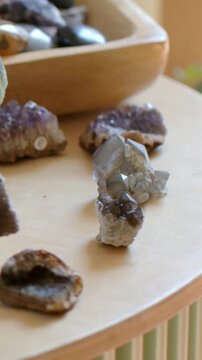 Vertical video: Panning camera focusing on quartz and druzy on wood table, revealing amethyst, bowl