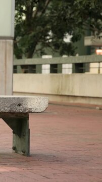 Vertical video: Framing bench in plaza with passersby walking behind to show plaza life, copy space