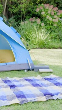 Vertical video: Panning camera in yard revealing tent opening and cushion for detail, copy space