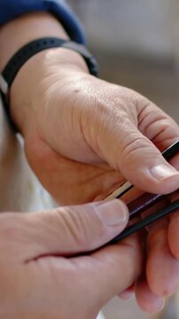 Vertical video: Right thumb pressing, senior hands sliding blade at home, checking knife with watch