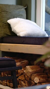 Vertical video: Framing white pillow as camera drifting to bench by window, revealing firewood