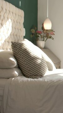 Vertical video: Entering sun sweeping across grid pillow and headboard from window, casting glow