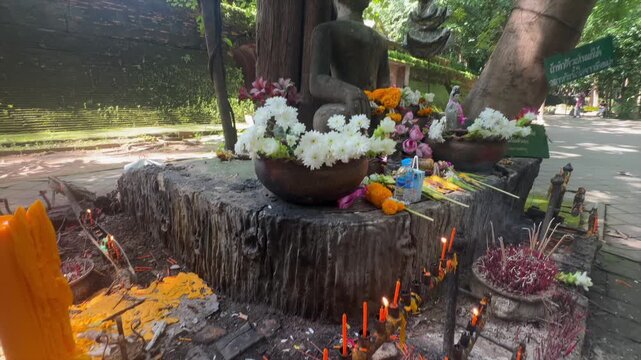 Burning candles and incense sticks at a Buddhist shrine in Wat Umong Suan Putthatham, Chiang Mai, Thailand. Devotees light candles and incense to offer prayers and seek blessings.