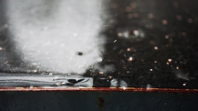 Macro close up view of water drops falling on hot griddle and instantly turning into steam.