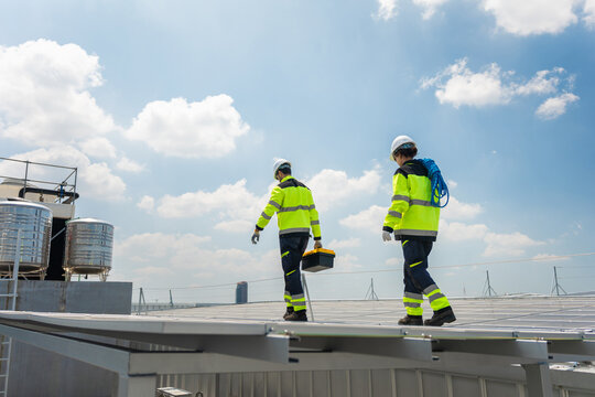 Team of engineers working on solar photovoltaic cell installation at industrial facility, Technicians team installing solar panels on commercial building rooftop
