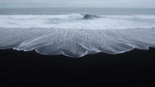 Natureblack sand beach with white wave ocean surf foam on volcanic shoreline, rolling tide under cloudy gray sky, dark coastline, dramatic moody coastal seascape nature background