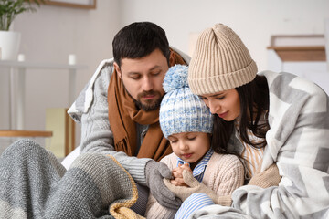 Obraz premium Frozen family with plaids and lack of heating holding hands in bedroom