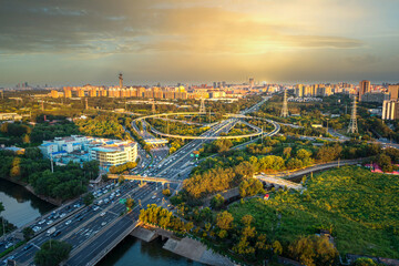 Obraz premium A panoramic aerial view of Beijing's multi-level transportation system and ecological livability under the golden sunset.
