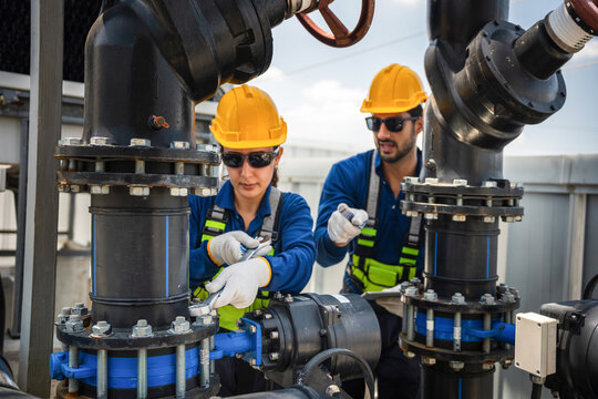 Team of engineers inspecting cooling equipment and water pump at industrial plant, Professional technician and worker performing maintenance on industrial HVAC and piping system on commercial rooftop