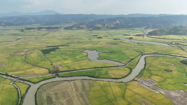 High Altitude Drone View of Rice Fields, Waterways and Rolling Hills in Evening Haze, Vietnam