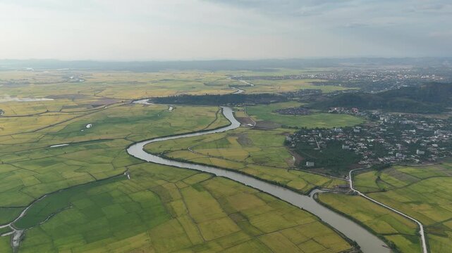 Drone Flight Over Vast Rice Fields Along a River With Rural Village at Sunset in Dak Lak, Vietnam