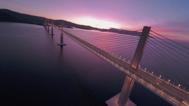 FPV drone perspective sweeping past the massive pillars of the Peljeski Most landmark. High-angle dynamic footage of contemporary civil engineering in the Balkans.