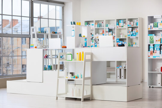 Modern pharmacy interior with white counters and shelves stocked with medications and health products, the clean, organized space is illuminated by natural daylight streaming through large windows