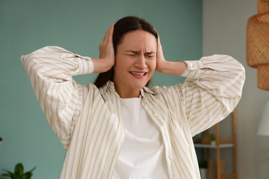 Young woman suffering from noisy neighbours at home