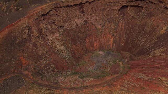 Aerial view of Mirador del Gayo volcano crater, showcasing its reddish geological landscape