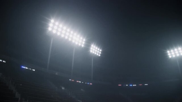 Bright stadium floodlights shining at night in a dark sports arena