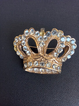 Luxury golden crown brooch pin decorated with crystal shiny rhinestones.