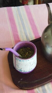 Vertical Closeup of Traditional Yerba Mate Gourd with Bombilla and Kettle on Wooden Tray